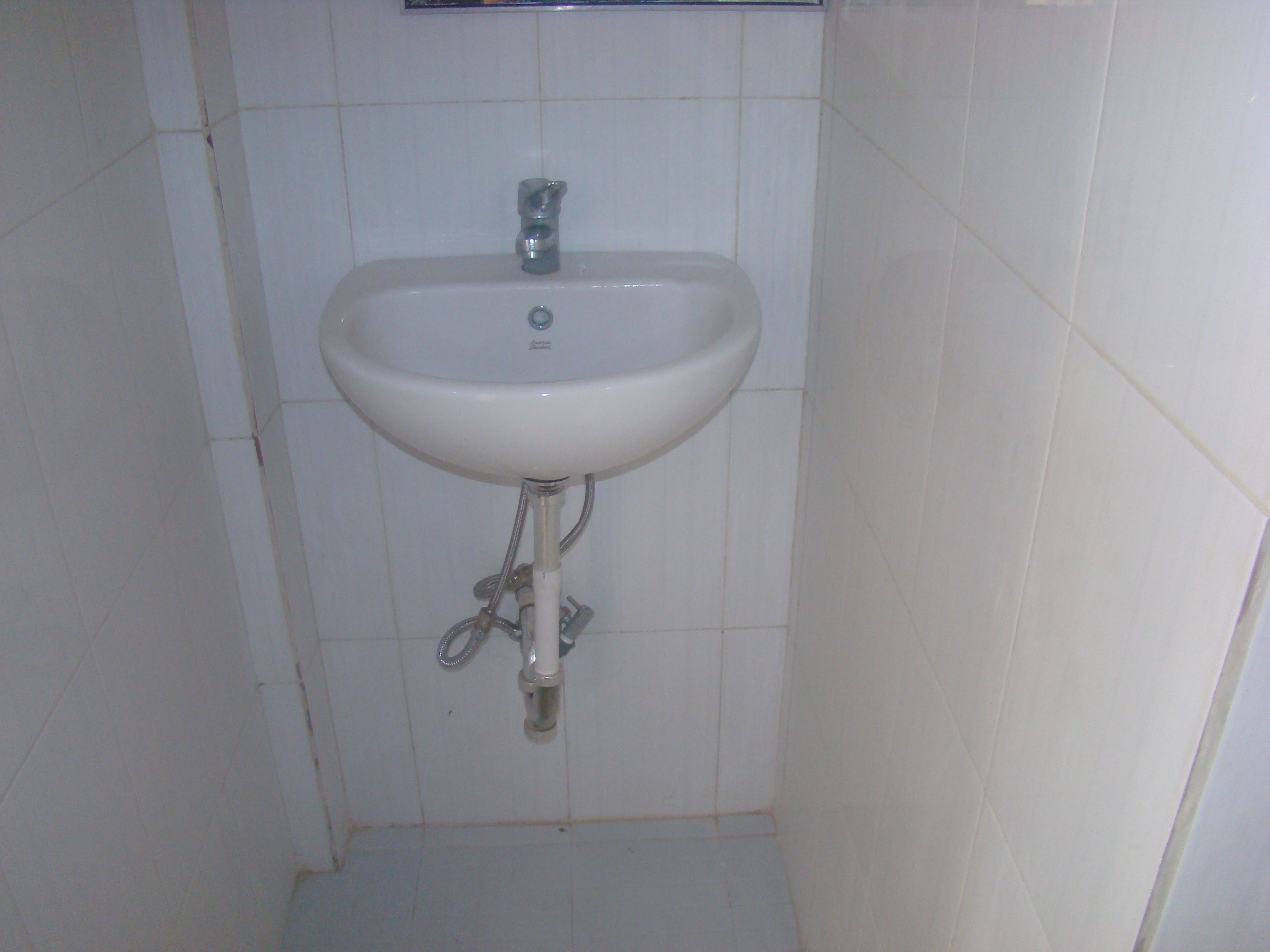A bathroom with a white sink, chrome faucet, and a single-handle design.