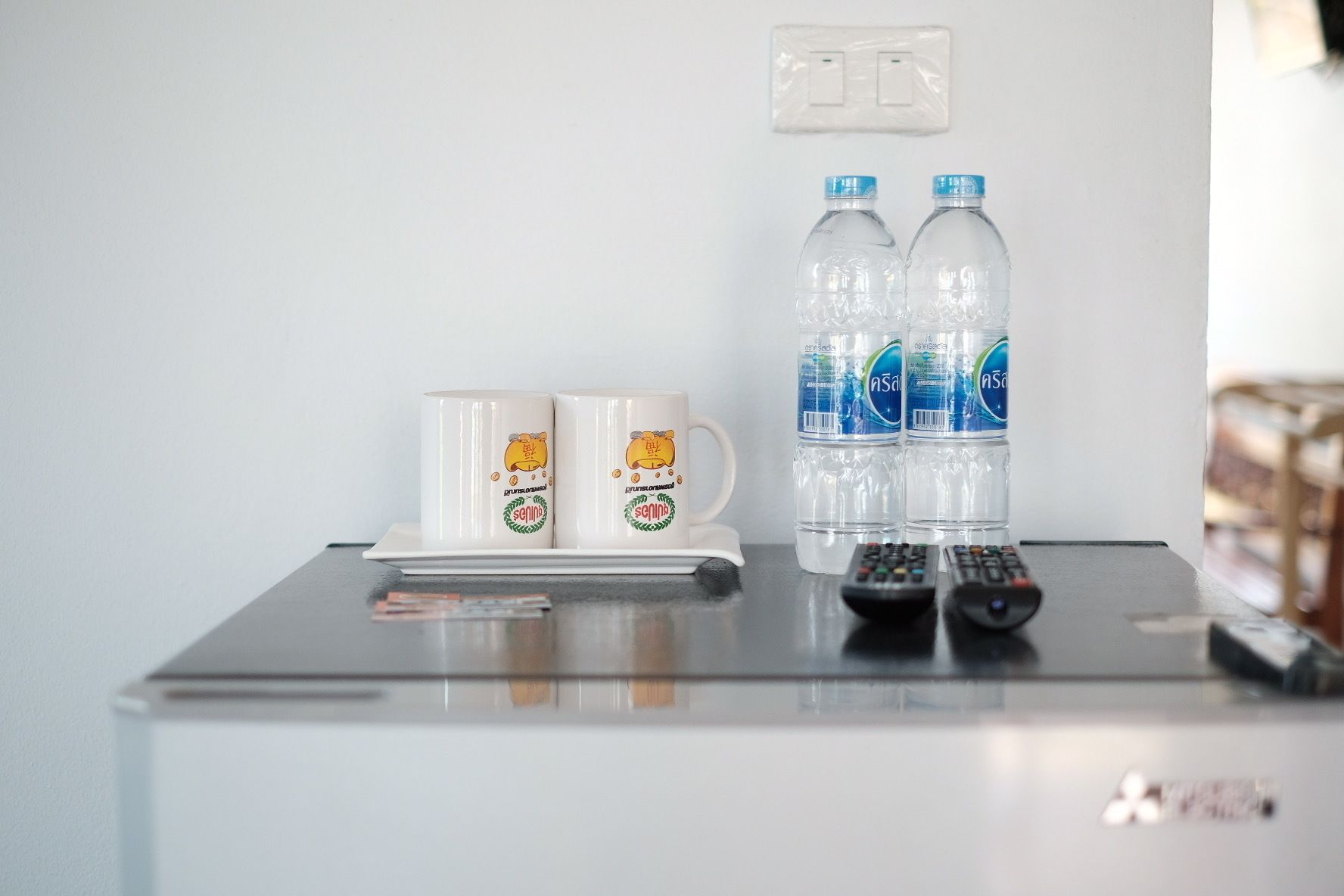 Uma pequena mesa com duas canecas, duas garrafas de água e dois controles remotos.