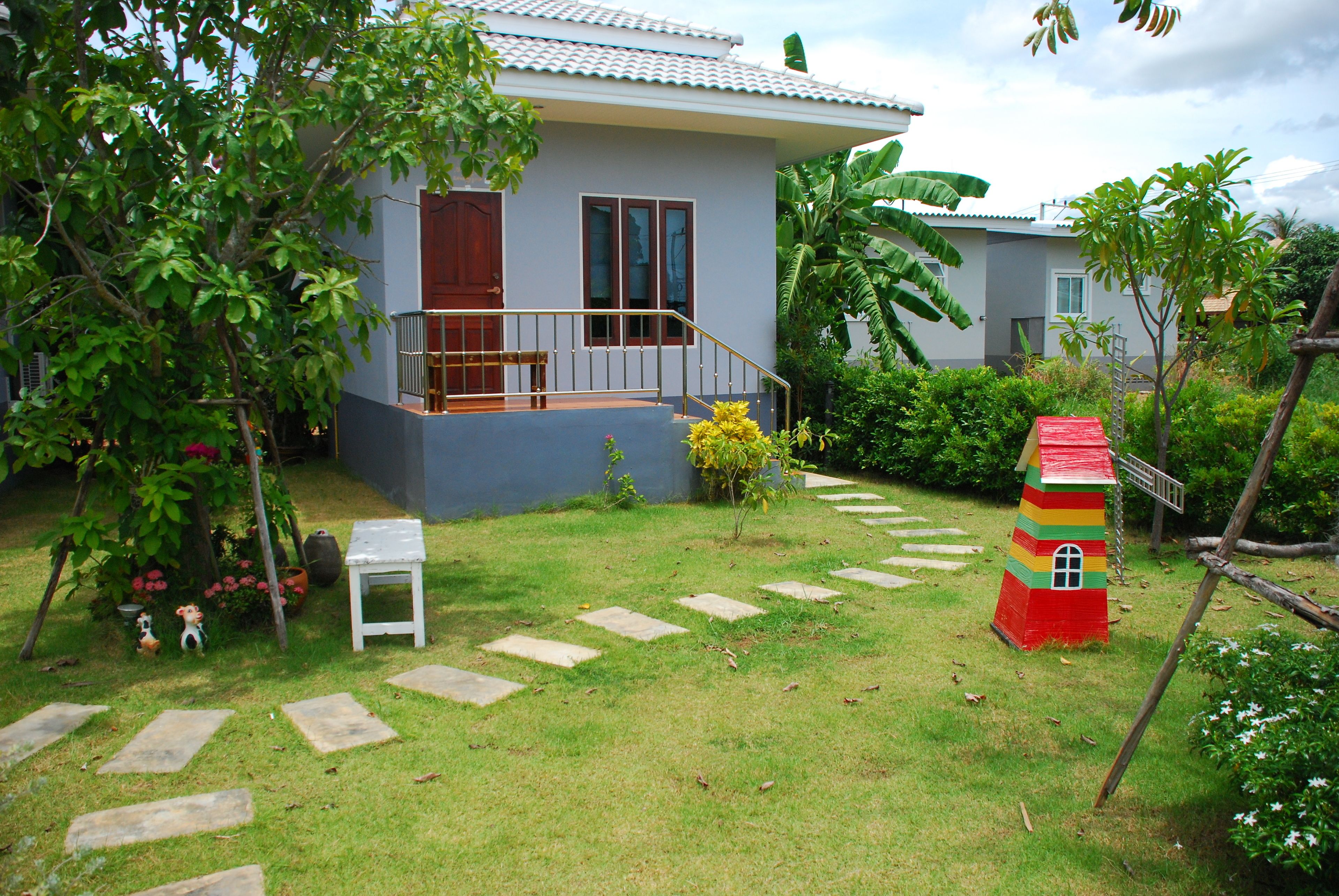 A house with a balcony, a small white table, and a colorful playhouse.
