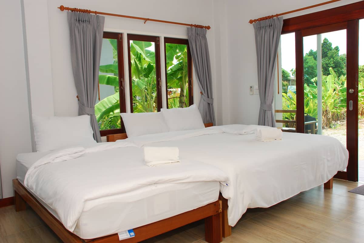 A double bed with white linens, a wooden frame, and grey curtains.