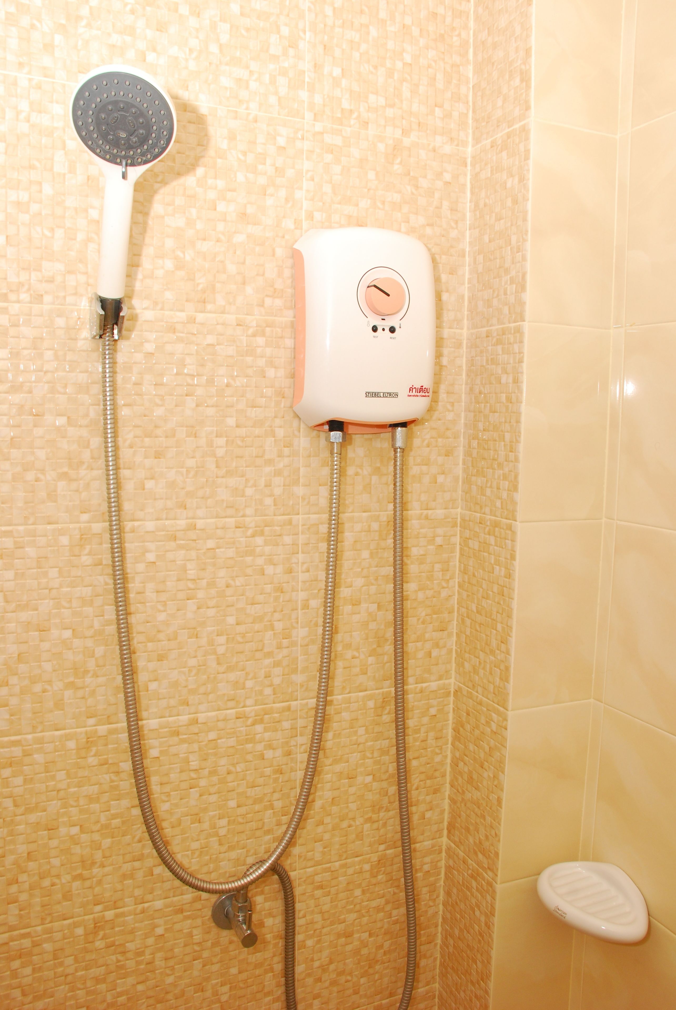 A shower with a handheld showerhead and a wall-mounted control panel.