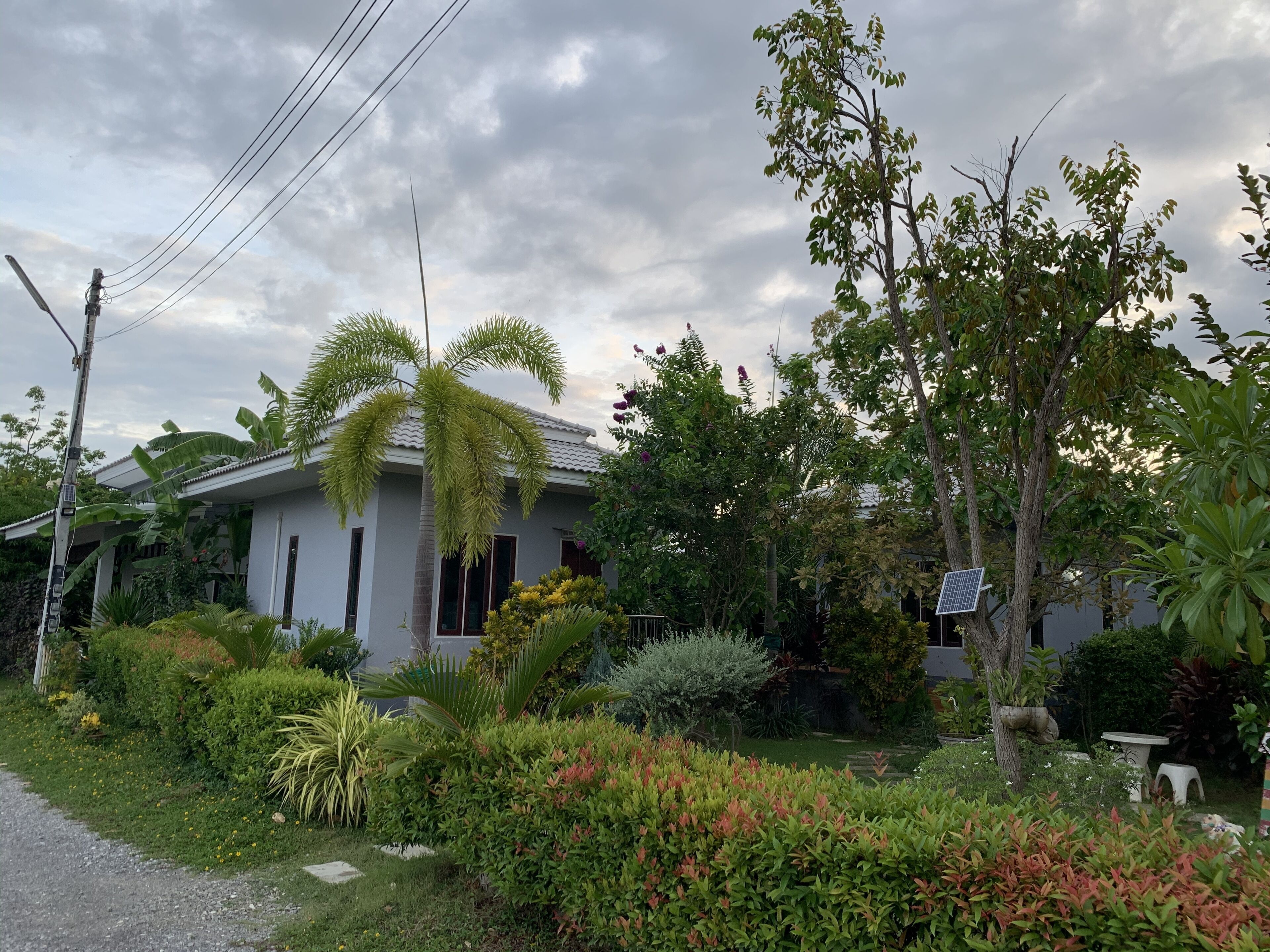 Une maison avec un jardin, un panneau solaire et un ciel dégagé.