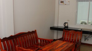 A compact room with a wooden dining table and chairs, a small kitchenette, and a window with a view. - Pran Kiang Lay (Pranburi)