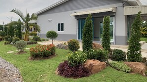 A modern two-story house with a well-maintained garden, including various shrubs and a palm tree. - Pran Kiang Lay (Pranburi)