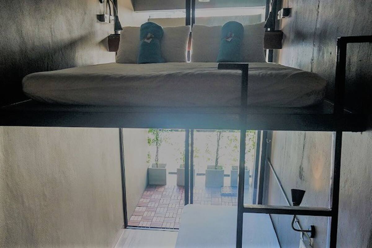 A bunk bed with a mattress, a window, and a view of the outside.