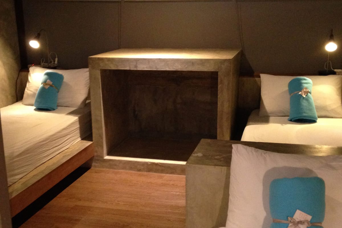 A hotel room with two beds, a small wooden table, and a nightstand with a lamp.