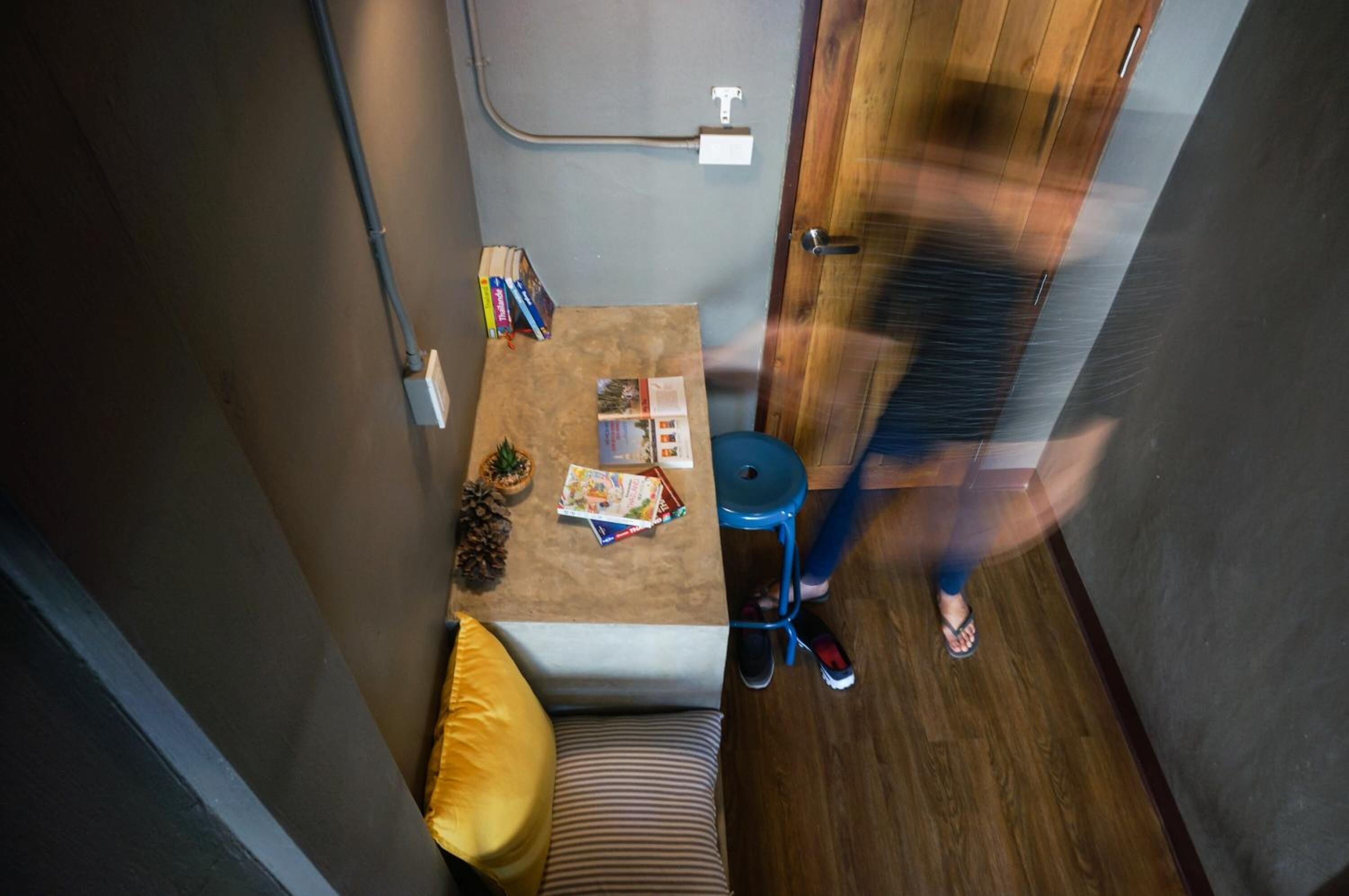 A compact room with a small table, a blue stool, a sofa, and a door.