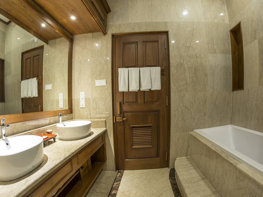 A bathroom with two sinks, a bathtub, and a wooden door with towels hanging on it.
