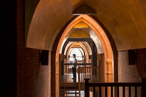 An arched brick corridor with a person standing at the end. - Heritage Bagan Hotel (Nyaung-U)