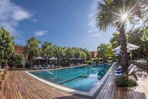 Una piscina al aire libre, sombrillas, tumbonas