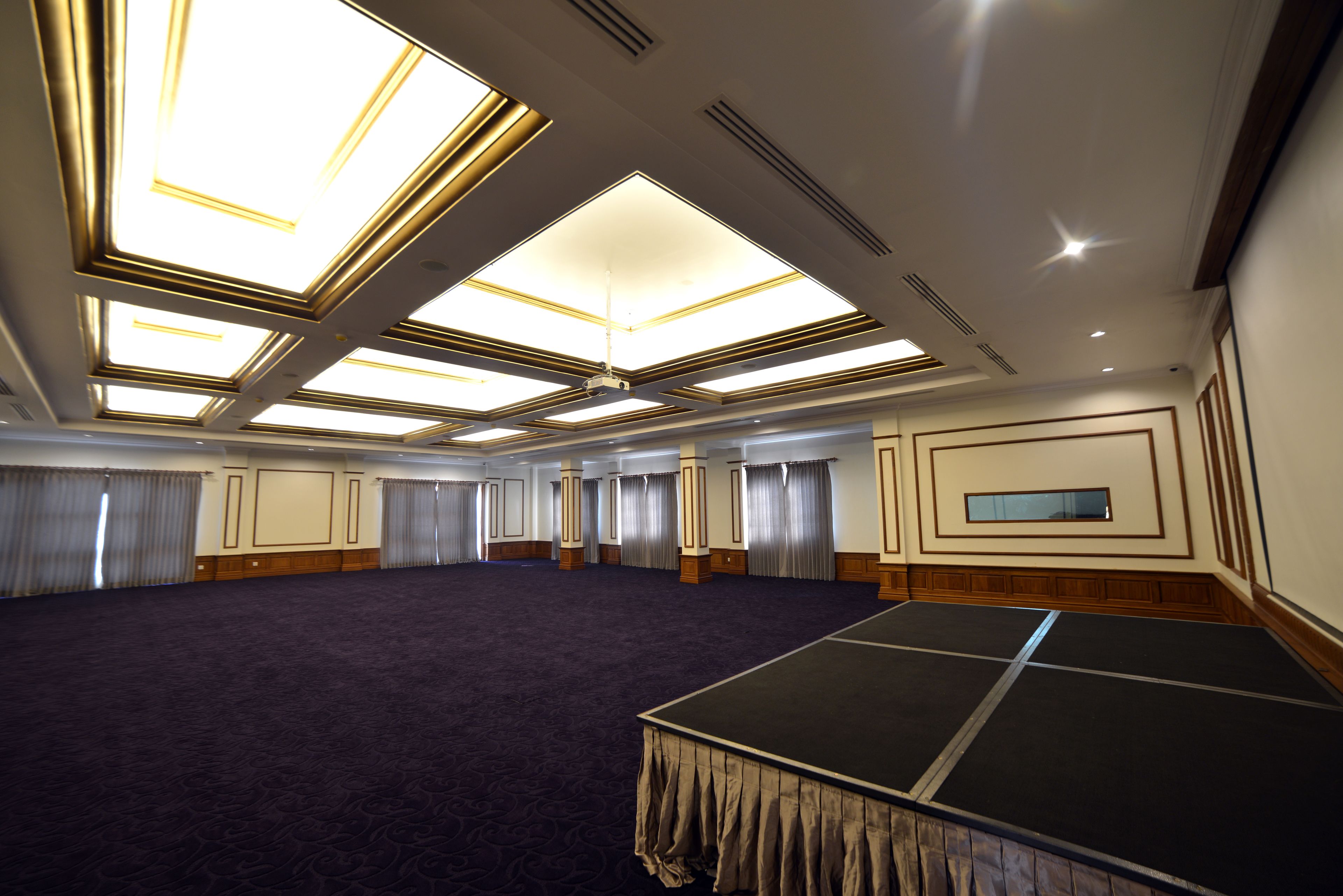 Un salón de conferencias amplio con techo alto, tragaluces y una zona escenario.