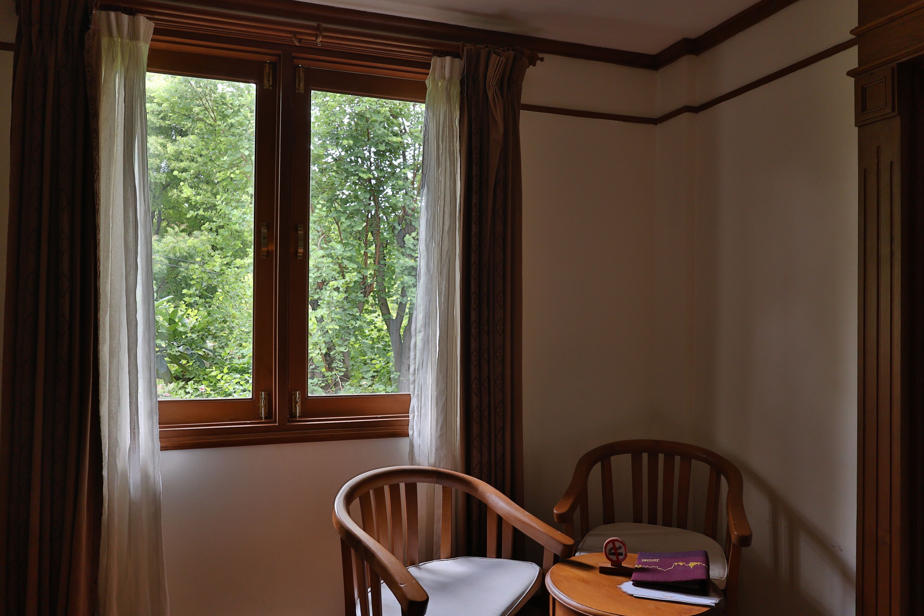 Una habitación con ventana, una silla y una mesa con un libro y una libreta.