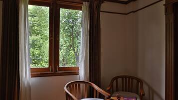 Una habitación con ventana, una silla y una mesa con un libro y una libreta.