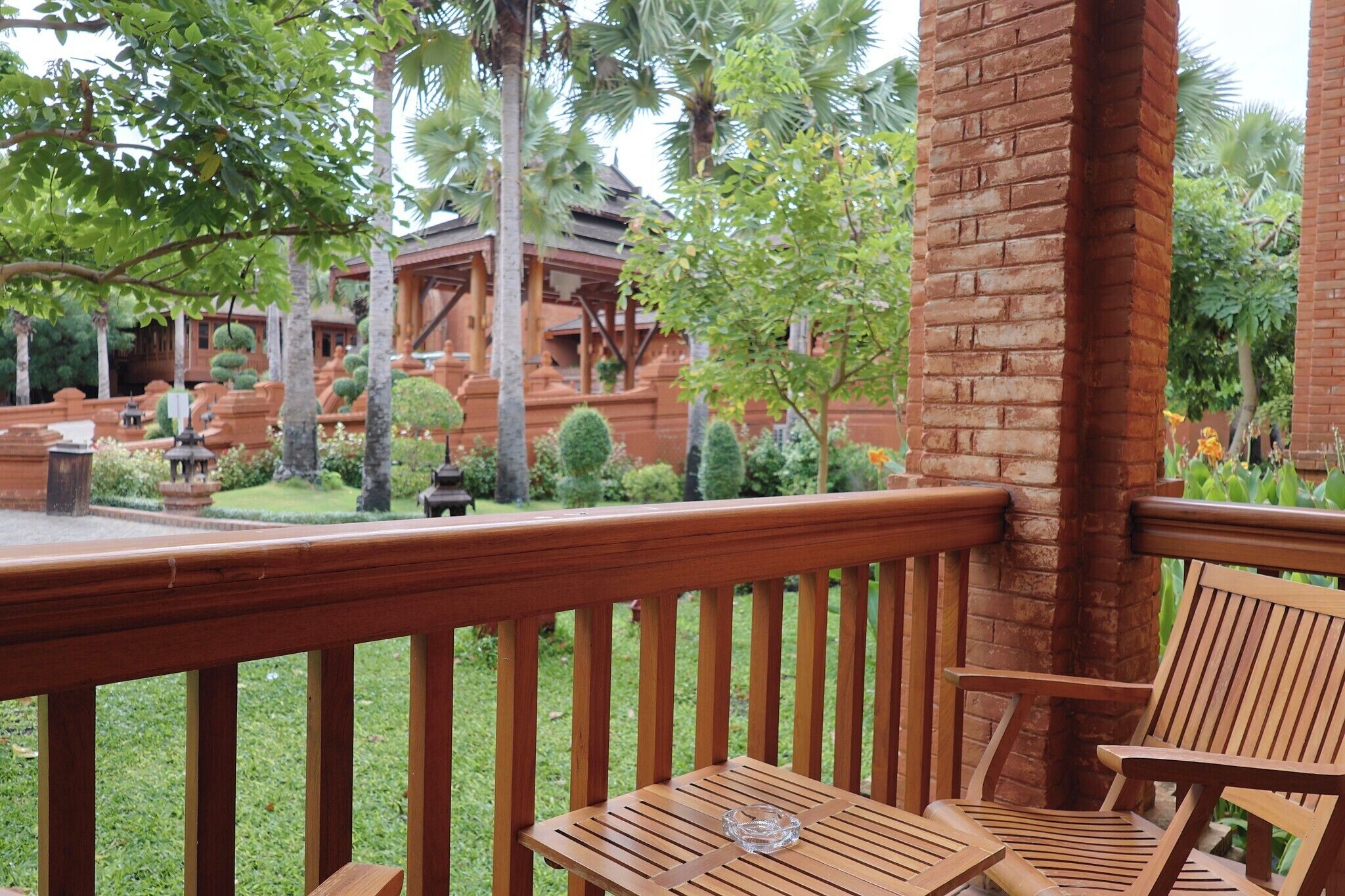 A wooden deck with a brick pillar, a table, and a chair.