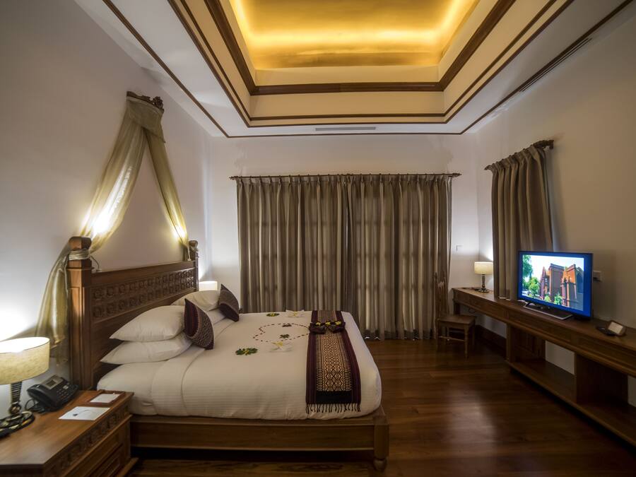 Una habitación de hotel con una cama grande, lámparas de noche, televisión y cortinas.