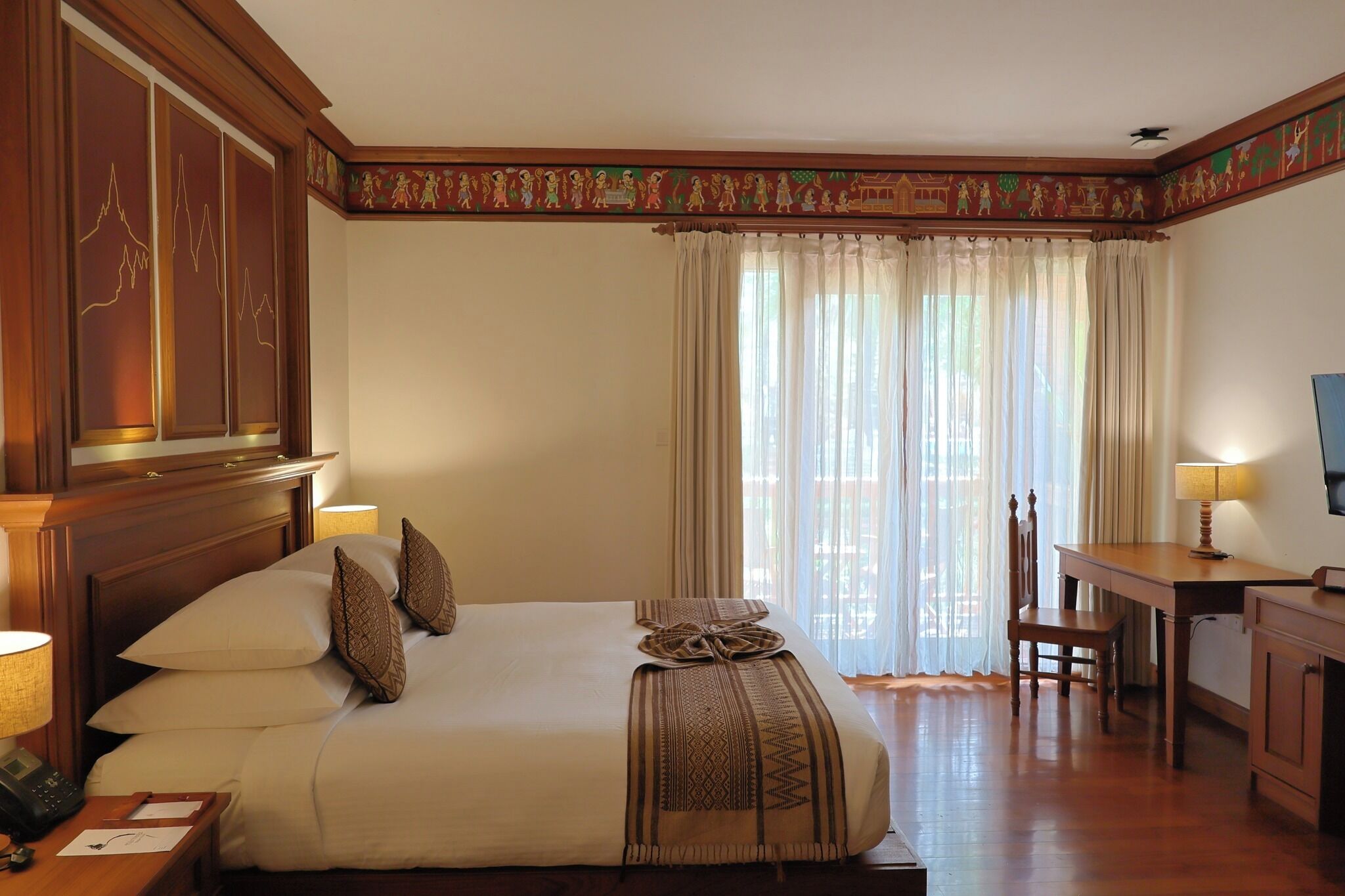 Habitación de hotel con una cama grande, un escritorio, una silla y un televisor.