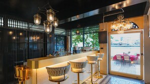 A bar area with high stools, a bar counter, and hanging lights. - Amdaeng Bangkok Riverside Hotel (Bangkok)