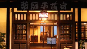 A traditional Japanese building entrance with a sign above the door, a lantern hanging in the center, and a small table with a vase on the right. - Yakushidaira Akanejyuku (Matsumoto)