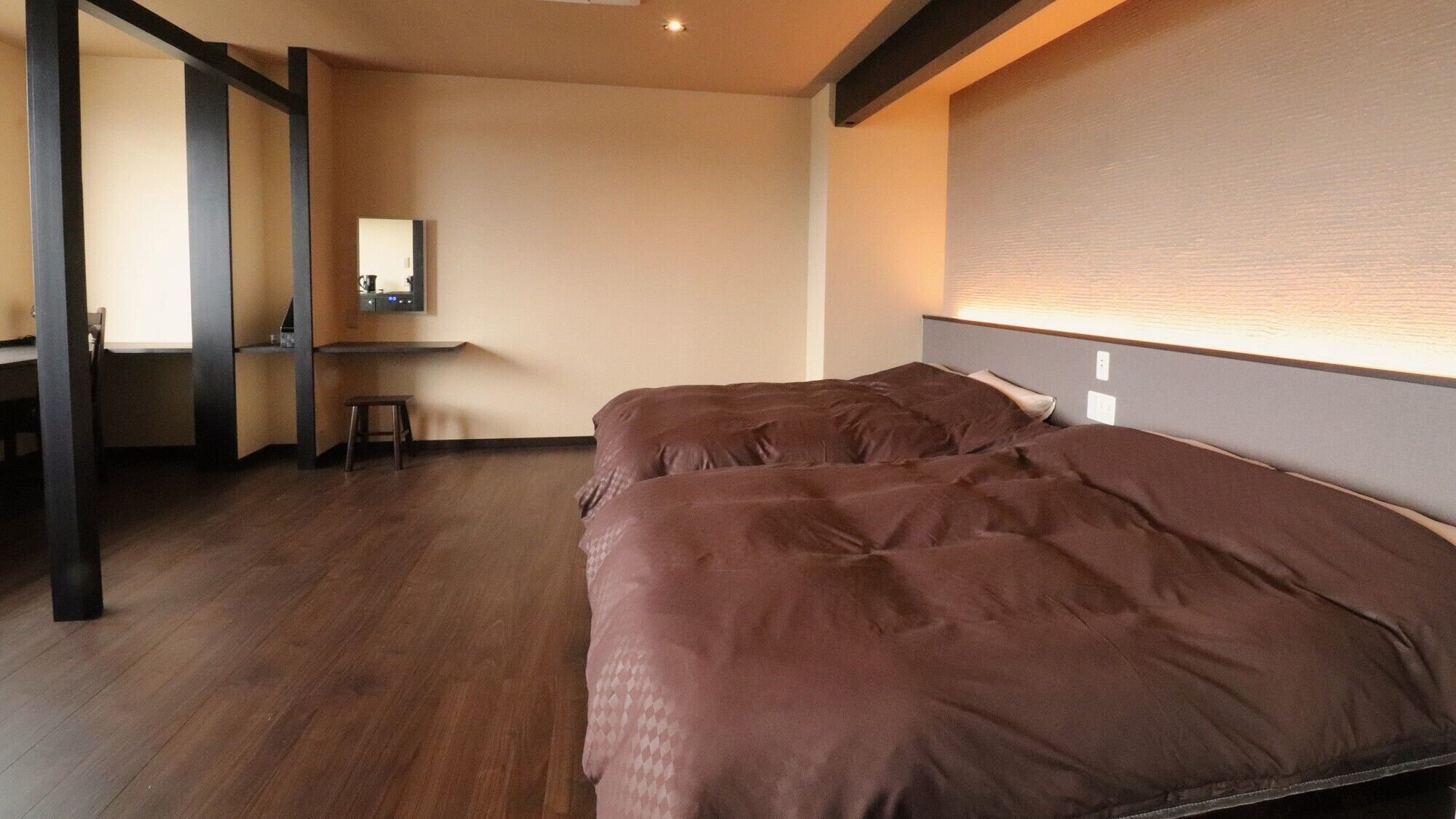 Una habitación de hotel con dos camas, un escritorio, una silla y un taburete pequeño.