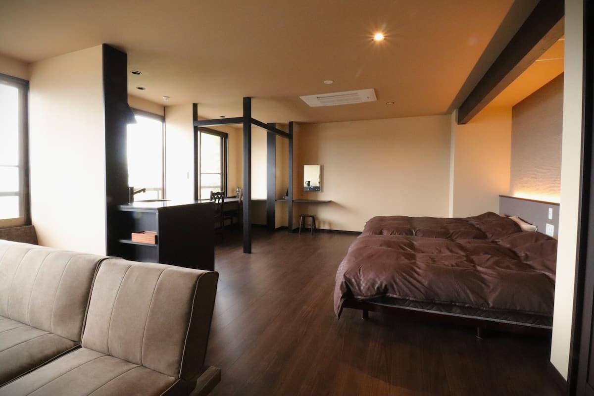 A modern hotel room with a bed, a sofa, a desk, and a chair.