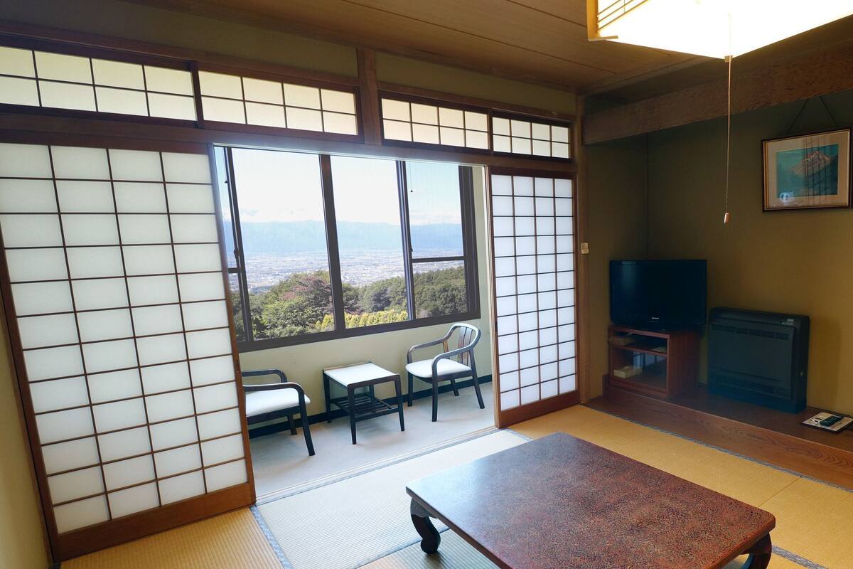 A traditional Japanese room with tatami flooring, a low table, and a television.