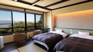 A hotel room with two beds, a view of the city, a small table, and a chair. - Yakushidaira Akanejyuku (Matsumoto)