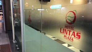 En glasvæg med Hotel Lintas Plaza logo og et cirkulært emblem.