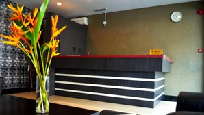 En receptionsdisk med et ur på væggen, en vase med blomster på et bord, og et gulv med et mønster.