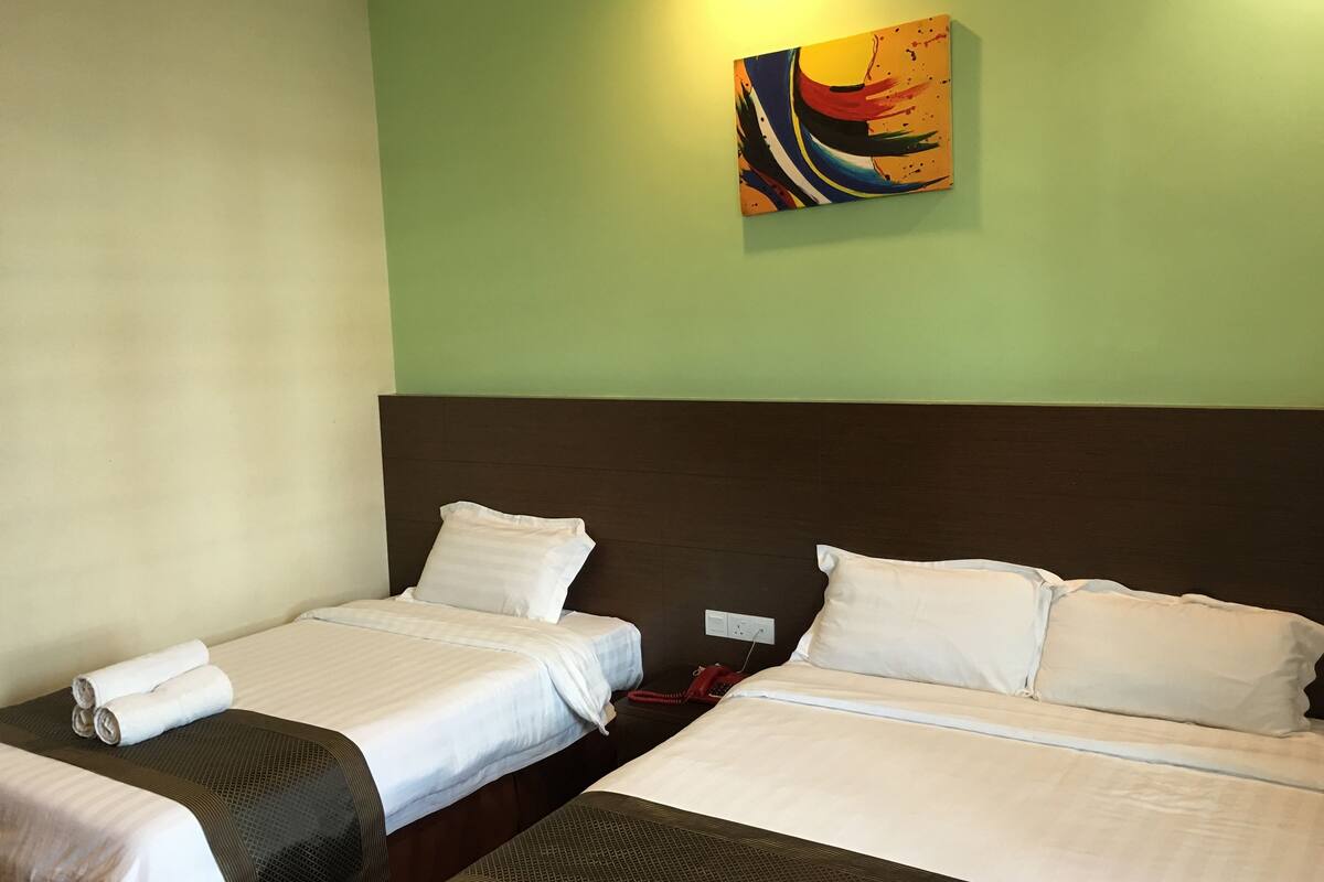Une chambre d’hôtel avec deux lits, une grande peinture abstraite au mur et un téléphone rouge sur la table de chevet.