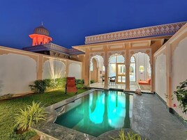 Un patio con piscina, vista a una mezquita y arquitectura tradicional.