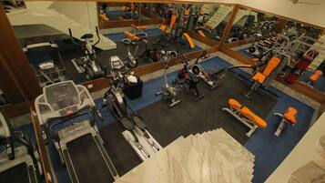 A gym with various exercise equipment, including treadmills, stationary bikes, and weight machines.