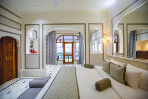 Habitación de hotel con una cama grande, un sofá, una puerta de madera y vistas al exterior.