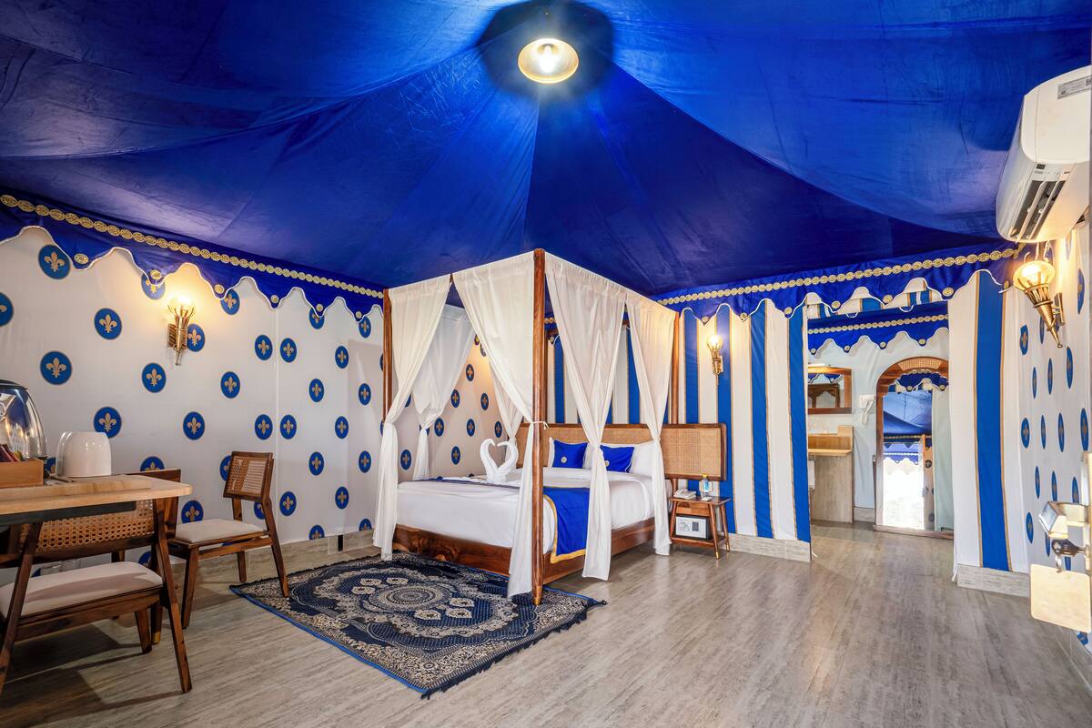Une chambre dotée d’un lit à baldaquin, d’un coin repas avec une table et des chaises, et d’un tapis à motifs.
