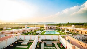 A resort with a swimming pool, multiple guest rooms, and a view of the surrounding landscape.