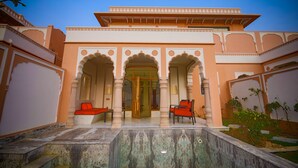 A traditional building with arched entrances, a marble pathway, and outdoor seating.