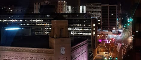 A night view of a cityscape with a prominent building featuring a clock and a sign for the Civic Theatre.