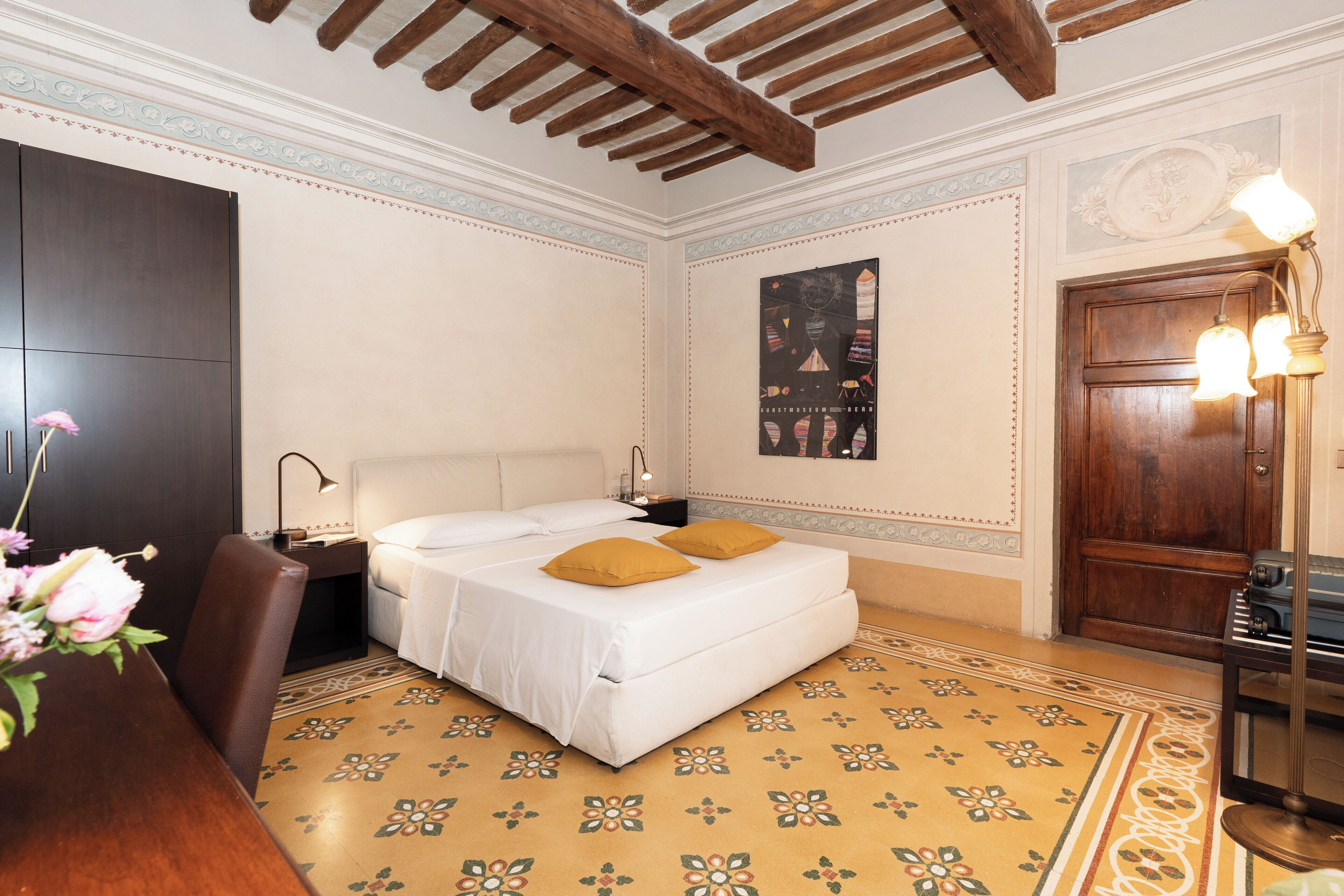 A hotel room with a bed, a nightstand, a desk, and a chair.