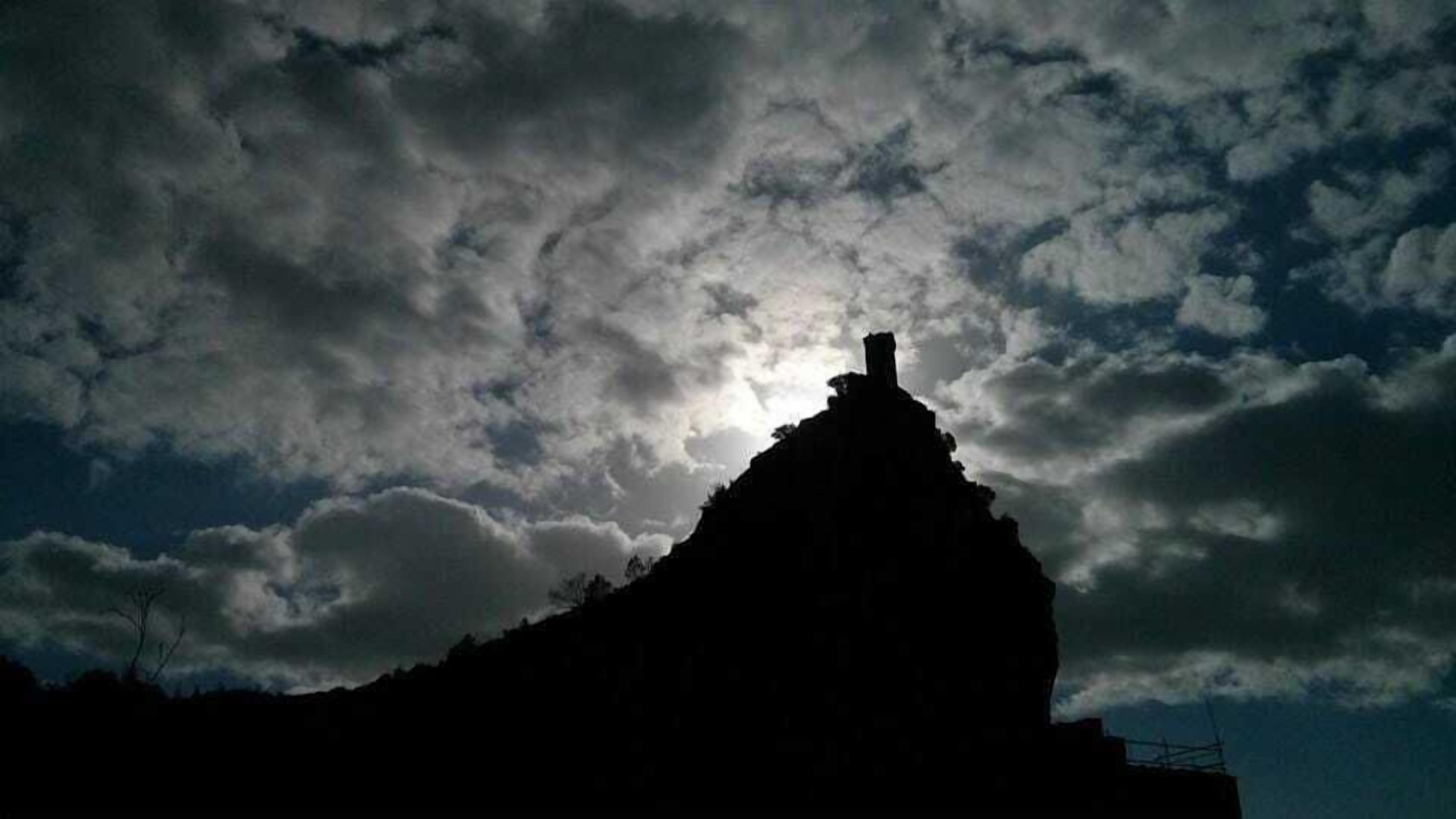 Silhueta de uma montanha contra um céu nublado.