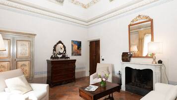 A room with a fireplace, a mirror, a wooden cabinet, and two white sofas.