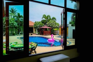 Una piscina con un flotador de flamenco, rodeada de palmeras y un pabellón.