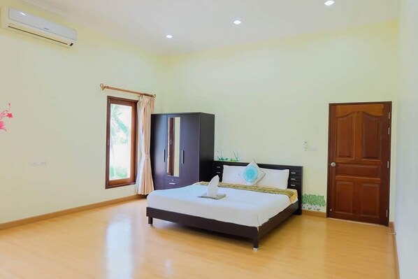 Un dormitorio con cama, armario, puerta y equipo de aire acondicionado.