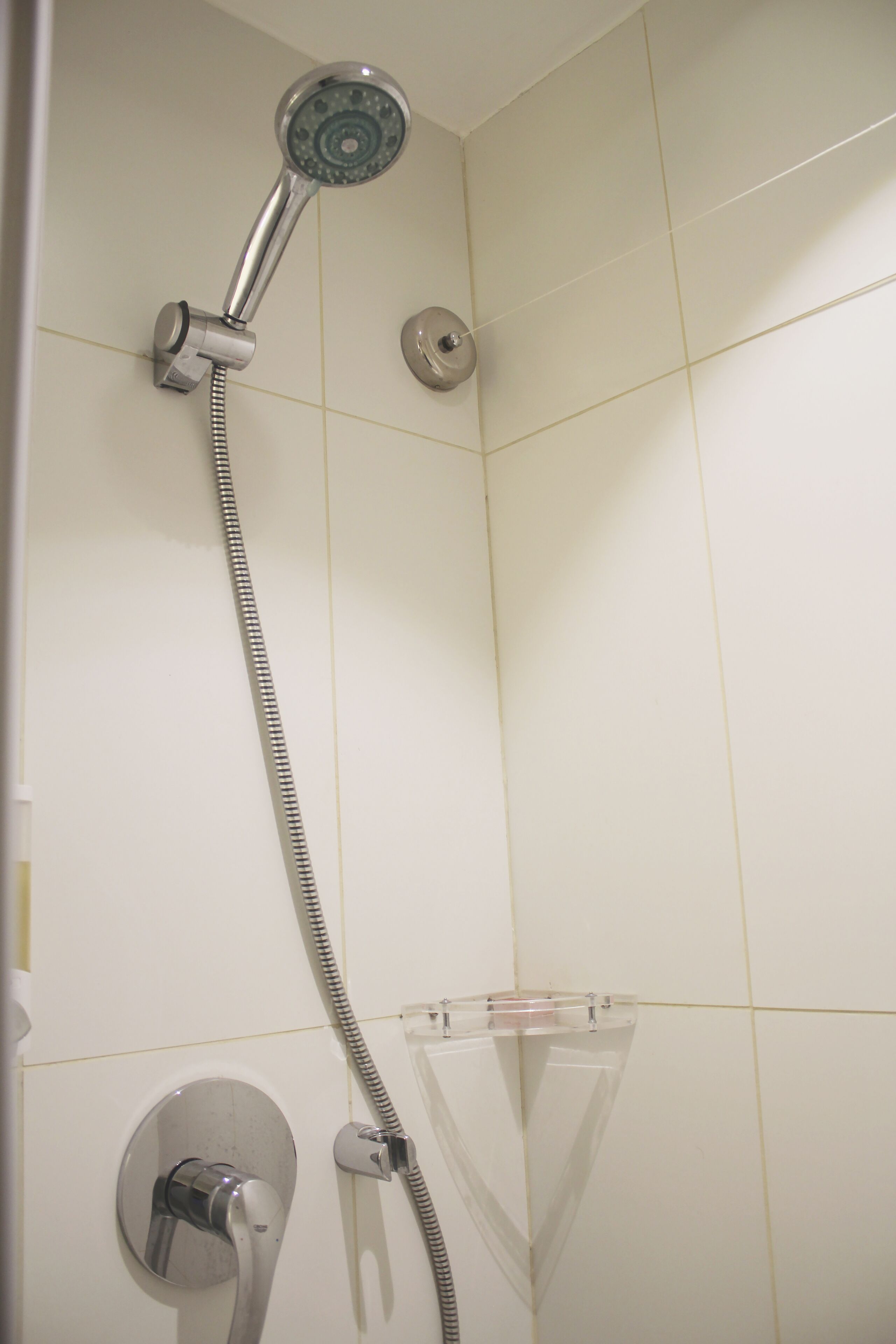 A shower with a handheld hose and a wall-mounted showerhead.