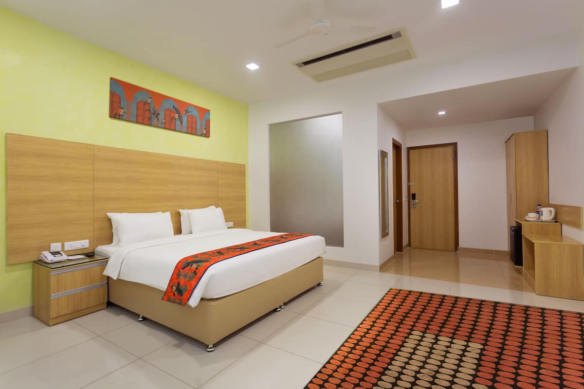 Una habitación de hotel con cama, mesita de noche y un cuadro en la pared.