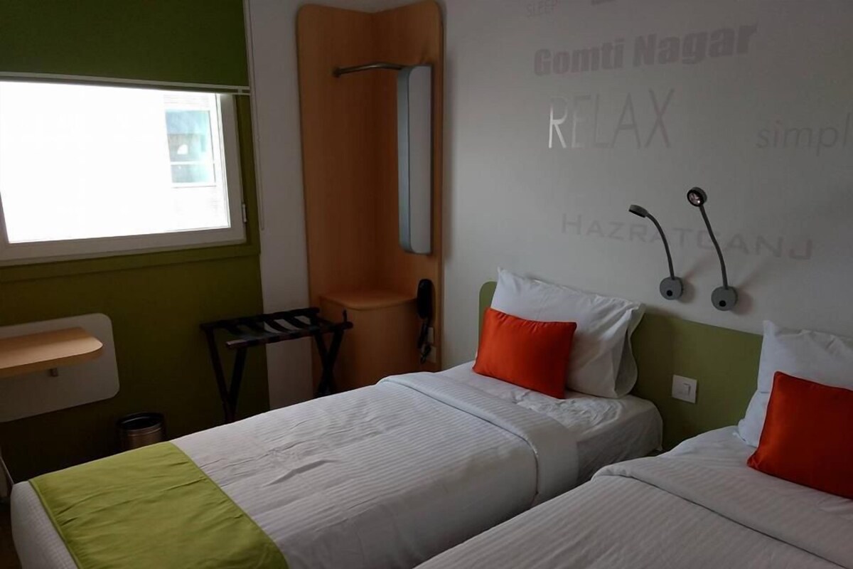 A hotel room with two beds, a window, a sink, and a mirror.