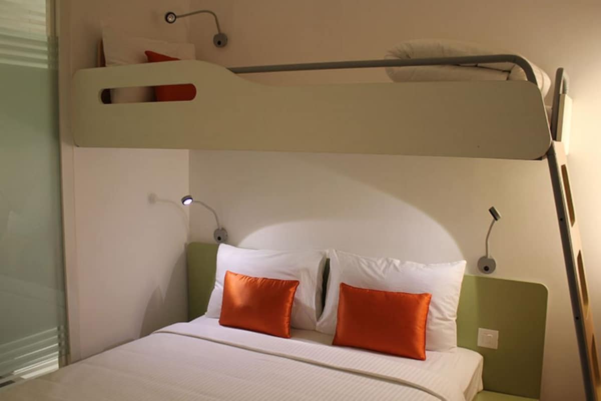 A bunk bed with two pillows, a bedside table, and a lamp.