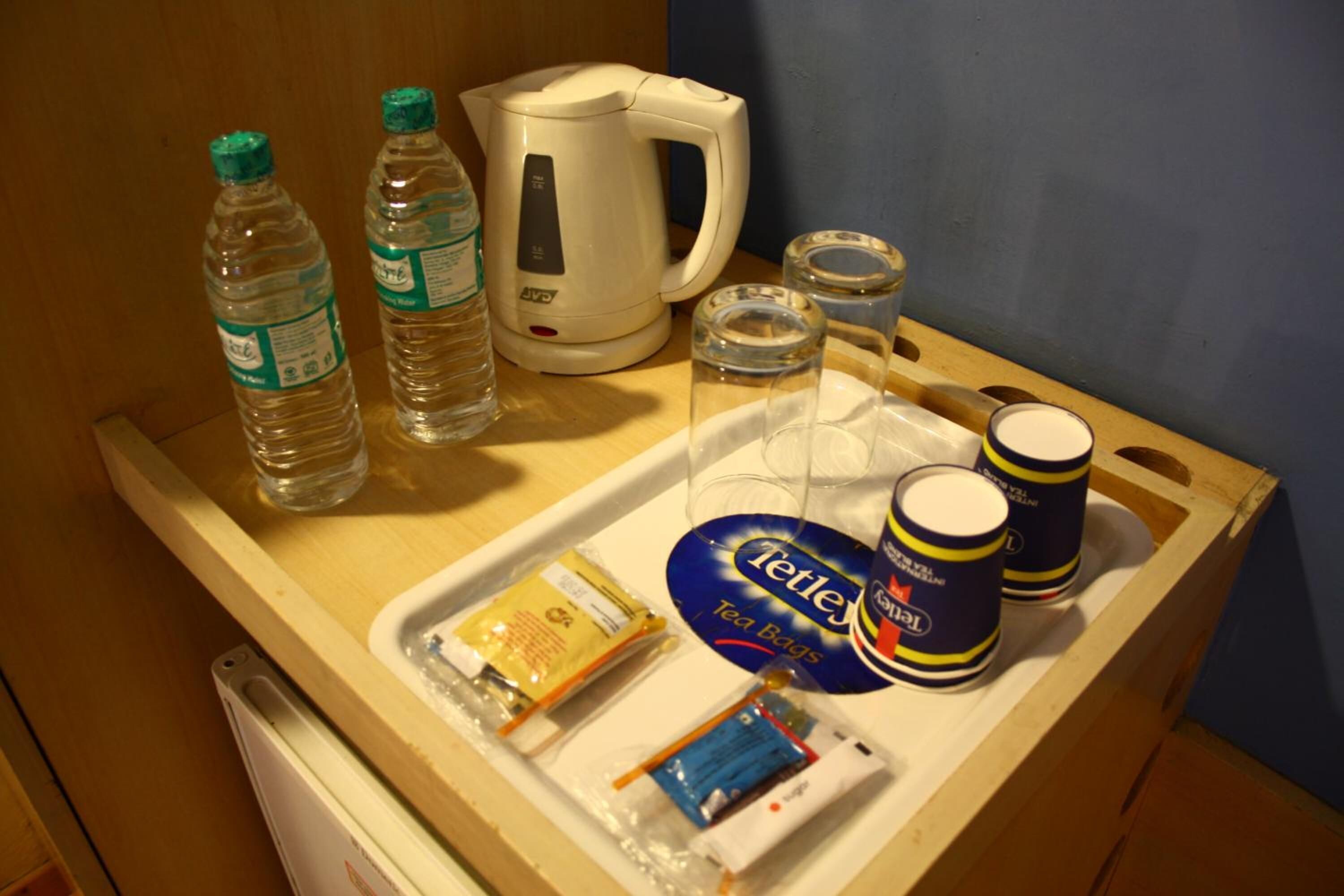 A tray with a kettle, bottled water, glasses, tea bags, and a container of tea.