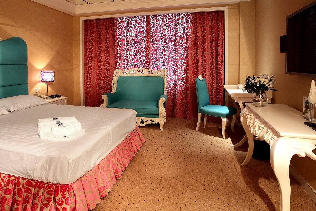 A hotel room with a bed, a chair, a desk, and a television.