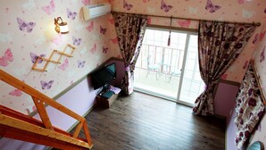 Ein Zimmer mit einer Holztreppe, einem Fernseher und einem Fenster mit Vorhängen.