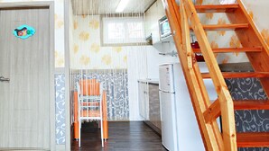 Eine Küche mit einer Holztreppe, einem Stuhl und einem Kühlschrank.