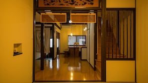 Um interior japonês tradicional com soalho de madeira, portas deslizantes e uma escadaria.